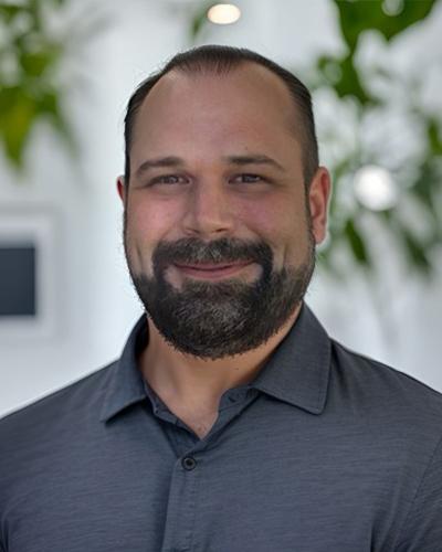 Cody, a smiling bearded man in a dark gray collared shirt